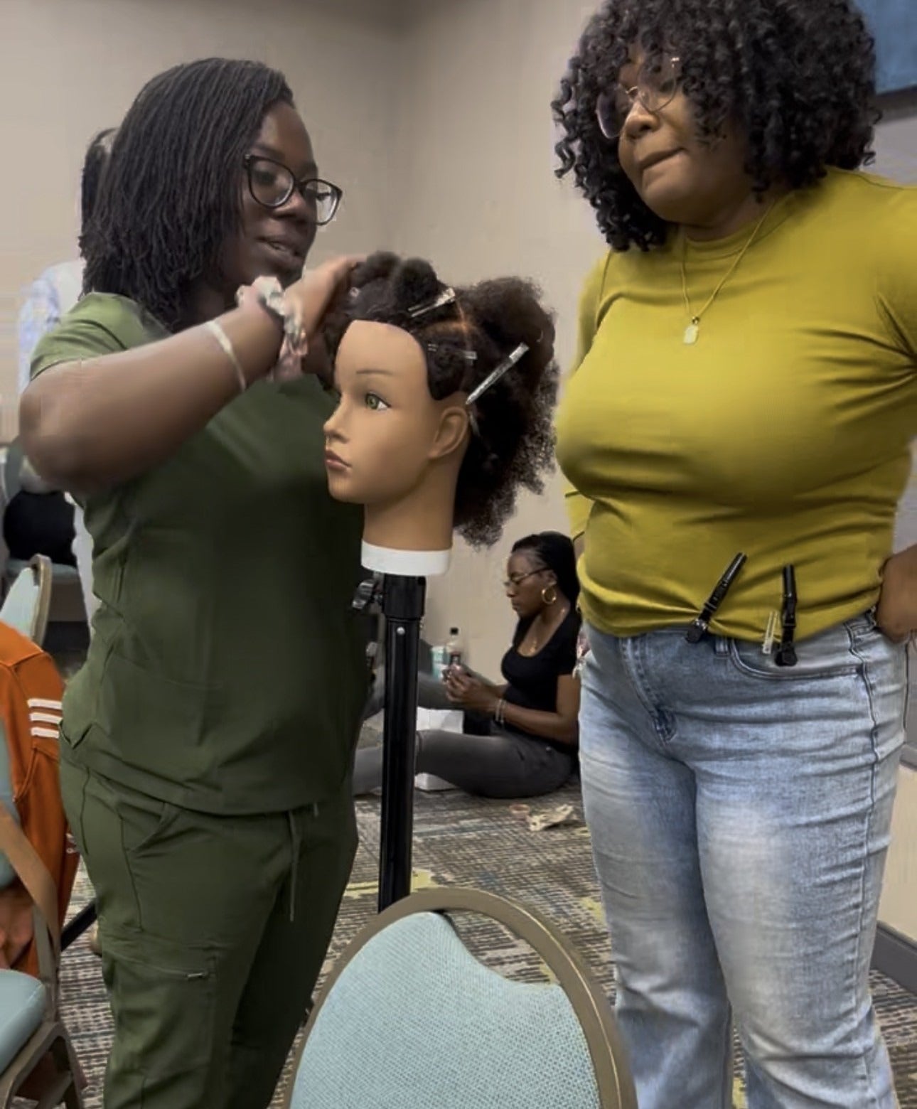 Tyler teaching microlocs technique on a mannequin during the certification class